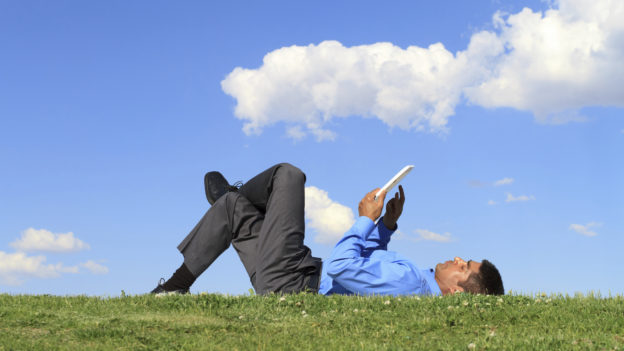 Man lying on the grass on tablet
