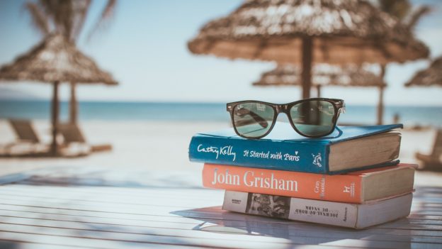 A picture of books on a table with a beach in the background