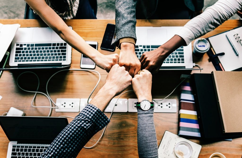 Colaboradores engajados com as mãos dadas e trabalho em equipe | Onboarding e Inboarding: o que são, diferenças e importância