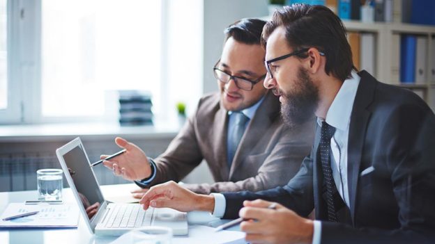 Imagem de chefe e empregado em frente ao pc | Como a tecnologia de RH pode ajudar a melhorar o engajamento