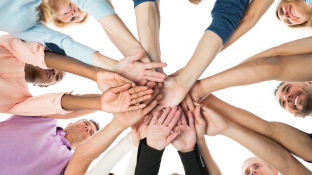 Imagem de equipa com mãos reunidas ao centro | 5 formas de melhorar o relacionamento ente os colaboradores